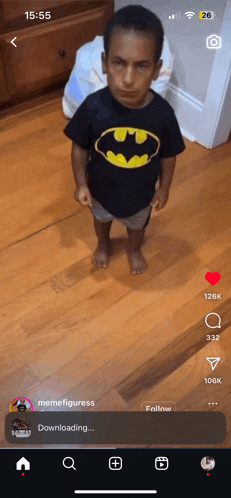 a little boy wearing a batman shirt is standing on a wood floor