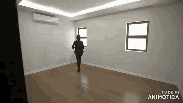 a woman is standing in an empty room with two windows