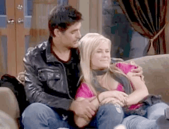 a man and a woman are hugging on a couch .