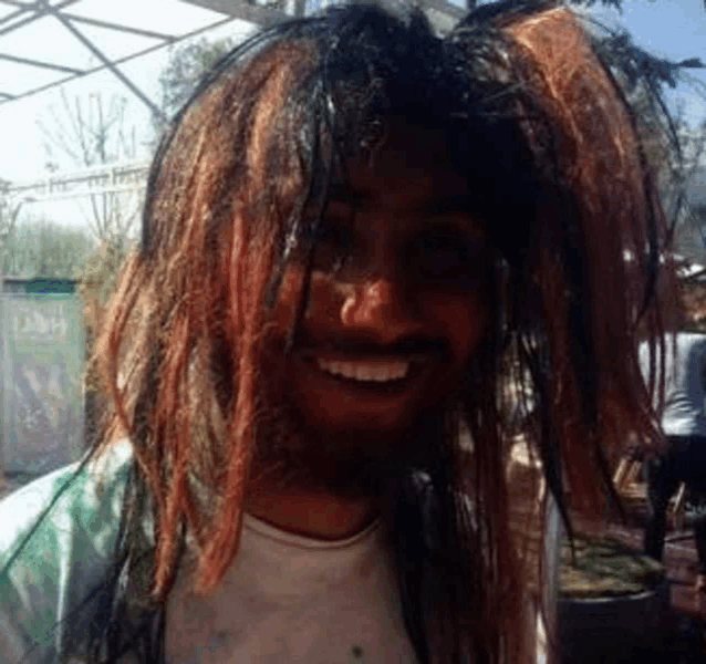 a man with dreadlocks and a beard is smiling .