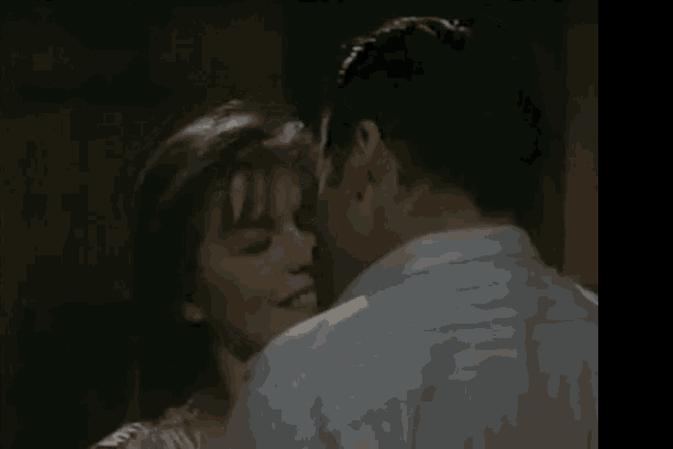 a man and a woman are kissing with the man 's shirt visible