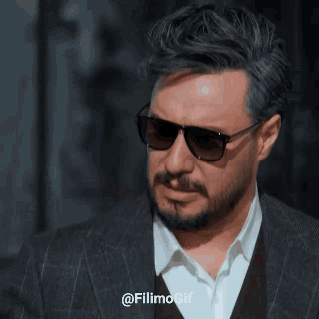 a man wearing sunglasses and a suit has the hashtag filimogif on the bottom left