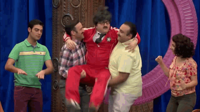 a man in a red jumpsuit is being carried by a group of men