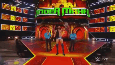a wrestler stands on a stage in front of a sign that says ' toer maha '
