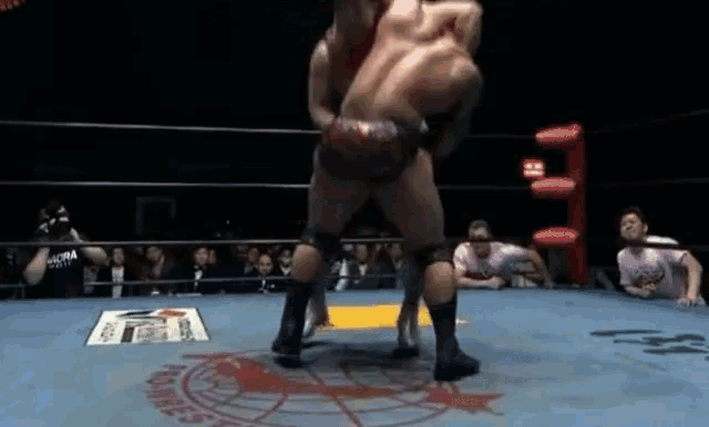two men are wrestling in a ring with the word hawks on the mat