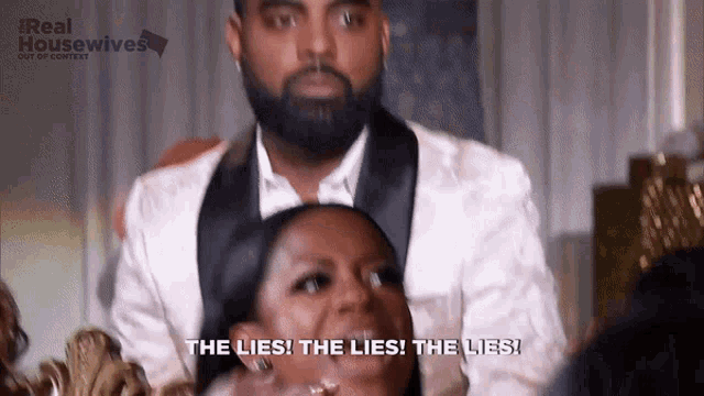 a man in a tuxedo is sitting next to a woman who is laughing and saying the lies the lies the lies .