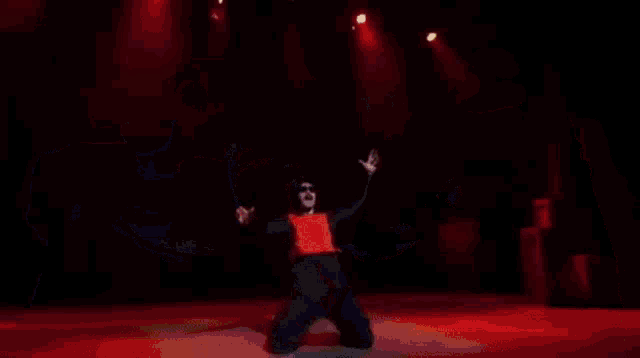 a man in a red vest is surrounded by two inflatable men in blue and yellow costumes on a stage .
