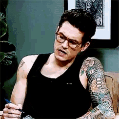 a man wearing glasses and a black tank top has a tattoo on his arm with the number 5 on it