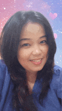 a woman in a blue shirt smiles for the camera with hearts in the background