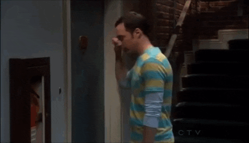 a man in a striped shirt is standing in front of a door and knocking on it .
