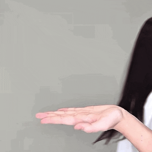 a woman wearing a white t-shirt with a red heart on it is pointing at someone 's hand