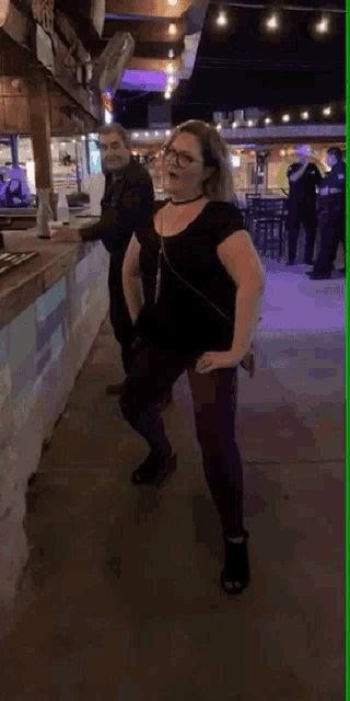 a woman wearing glasses is dancing in front of a group of police officers