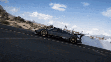 a black sports car is driving down a road in the desert