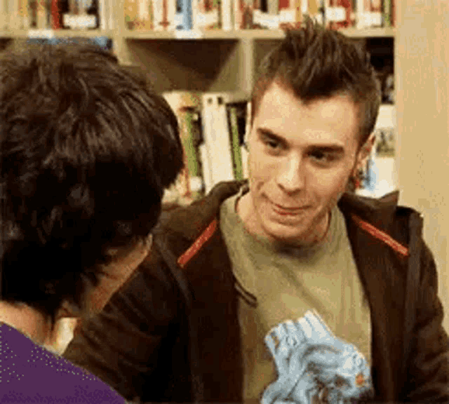 two young men are standing next to each other in a library .