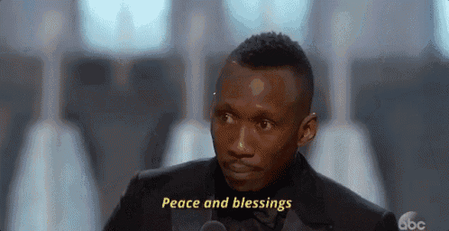 a man in a suit is talking into a microphone and says peace and blessings .