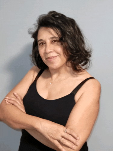 a woman in a black tank top with her arms crossed smiles for the camera