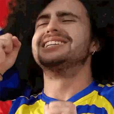 a man with a beard is wearing a blue and yellow striped shirt and making a funny face .