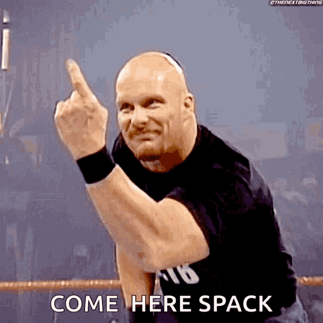 a bald wrestler is giving the middle finger and says come here spack
