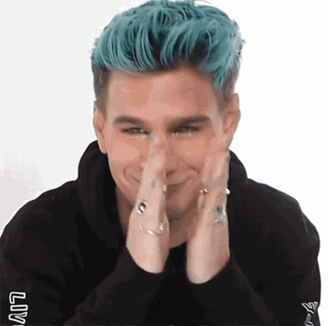 a man with blue hair is wearing a black hoodie with the word liv on the sleeve .