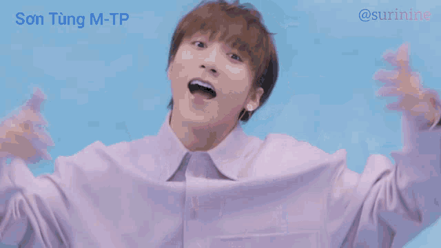 a man in a purple shirt making a heart with his hands
