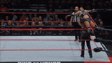 a female wrestler is being lifted in the air by a referee in a wrestling ring