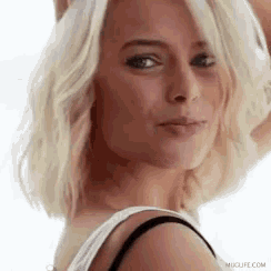 a close up of a woman 's face with blonde hair wearing a black bra .