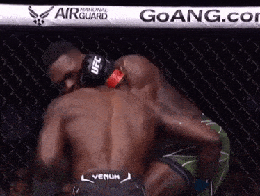 a man wearing a ufc glove holds another man in a wrestling ring
