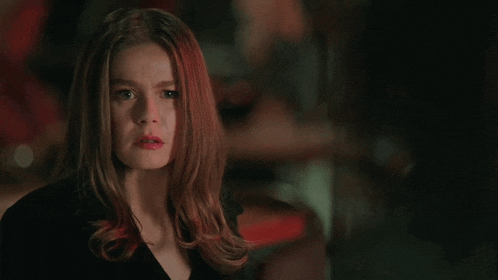 a woman with red hair looks at the camera