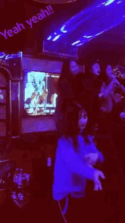 a girl in a blue shirt is dancing in front of a sign that says yeah yeah !!