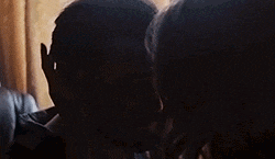 a man and a woman are kissing in a room .