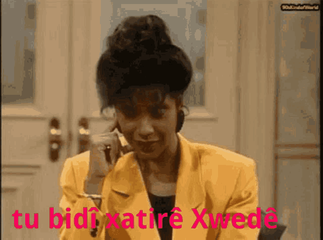 a woman in a yellow jacket is talking on a cell phone with the words tu bidixatiere xwede written in red