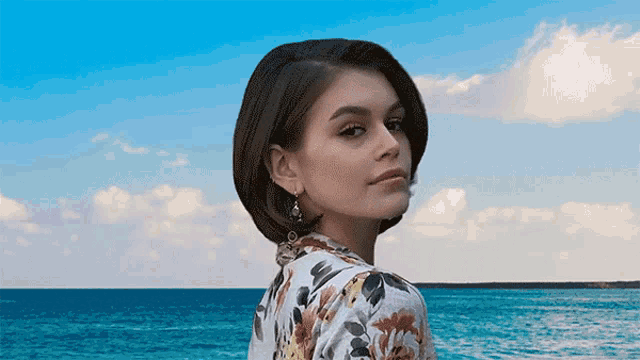 a woman stands in front of a blue ocean