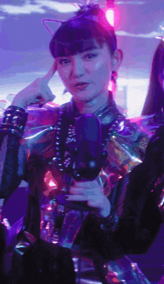 a woman wearing a cat ear headband holds a microphone