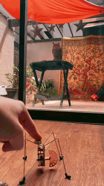 a person playing with a toy on a wooden floor in front of a window