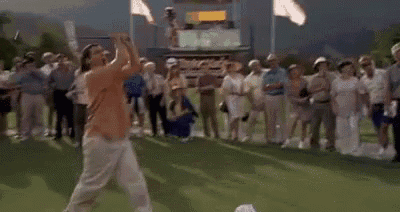 a man is playing golf on a green while a crowd watches .