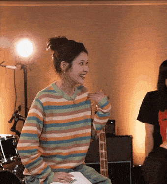 a woman in a colorful striped sweater is smiling