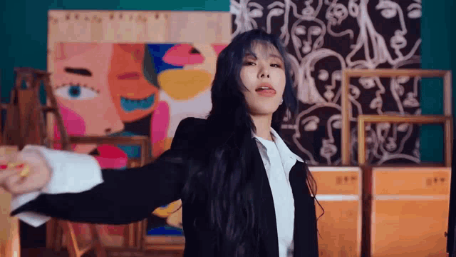 a woman in a suit and white shirt is standing in front of paintings .