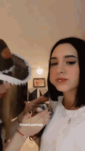 a woman is holding a small animal in her hands while standing next to a man wearing a mask .