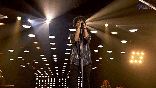 a man singing into a microphone on a stage with the word talent on the bottom right