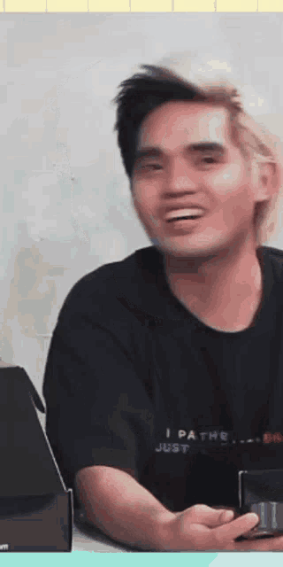 a man wearing a black shirt that says i pathe just smiles