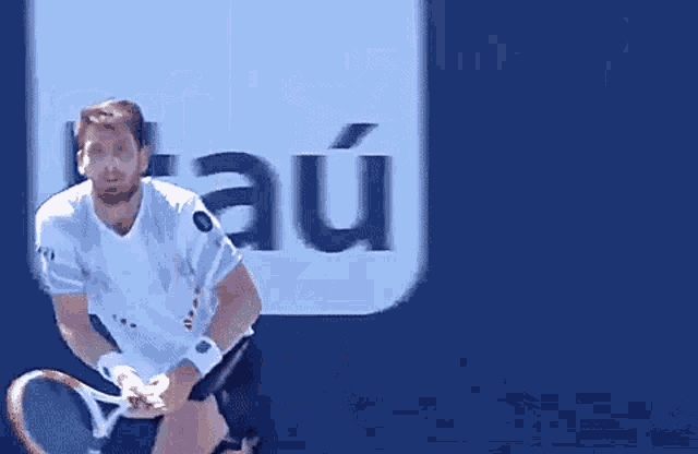 a man is holding a tennis racquet in front of a sign that says au