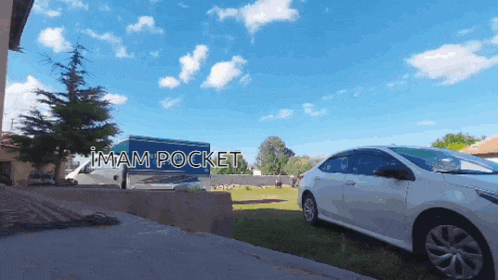 a white car is parked in front of a blue truck that says imam pocket on it