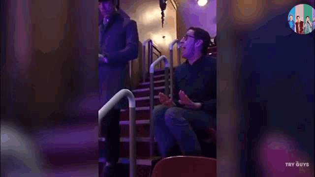 a man is sitting in a theater watching a show and laughing