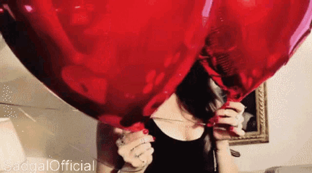 a woman is blowing up a heart shaped balloon with the words sadgal official written on the bottom