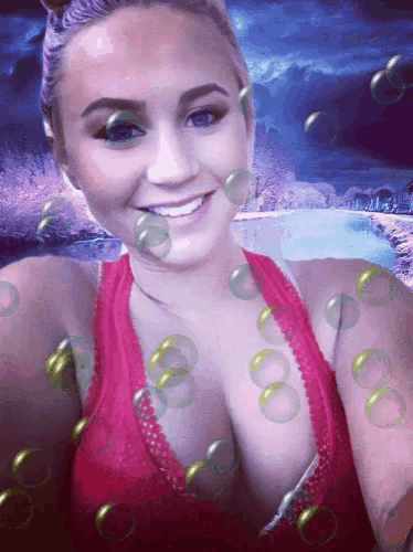 a woman in a red tank top is smiling with soap bubbles surrounding her