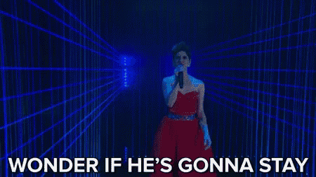 a woman in a red dress is singing into a microphone in front of a blue light .