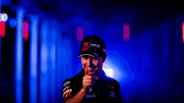 a man wearing a red bull hat giving the thumbs up sign