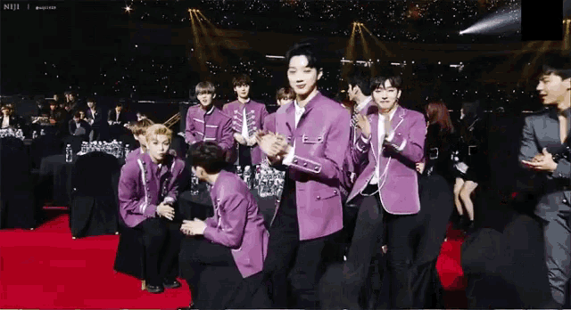 a group of young men in purple jackets are clapping