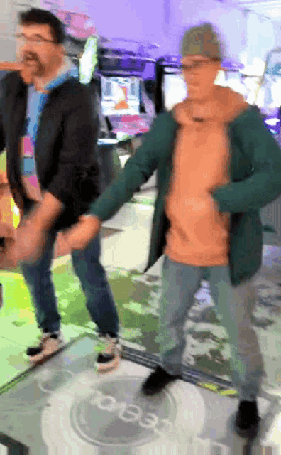 two men are holding hands while dancing in front of a sign that says ' oeee '