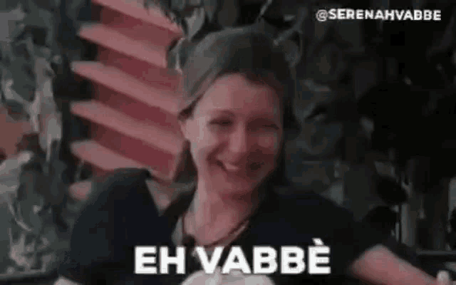 a woman is smiling and making a funny face with the words `` eh vabbe '' written on her face .